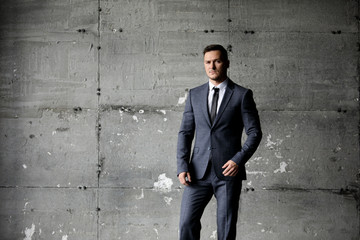 Handsome caucasian businessman dressed in the suit near the window in the loft interior studio