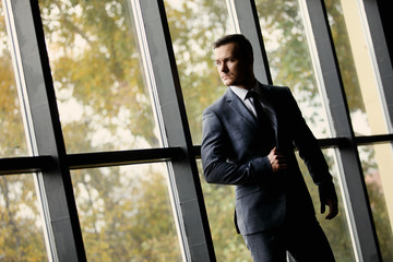 Handsome caucasian businessman dressed in the suit near the window in the loft interior studio