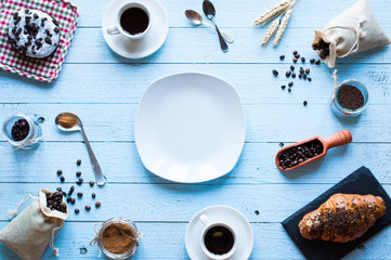 Coffee beans and cup of coffee with other components on different wooden background.