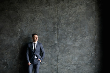 Portrait of stylish male dressed in a suit over grey background