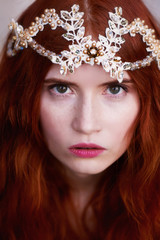 Portrait of a beautiful redheaded girl with long curly hair. Bride. With handmade jewelry on the hair. Hair to the waist. Very long red hair. Big facial