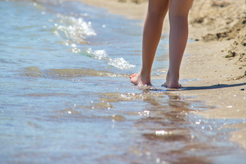 Closeup of a female's bare feet walking at a beach at the morning. Concept of the travel,vacation.