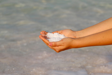 Fototapeta na wymiar Dead Sea, in the hands of a girl salt sea spa
