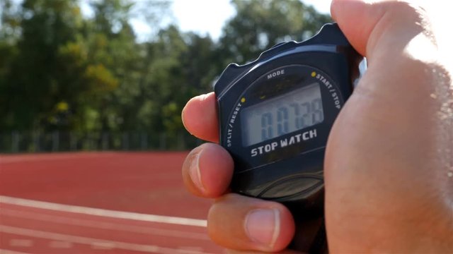 Stopwatch in hand and female runner athlete on stadium