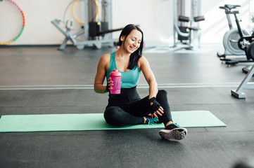 Young woman drinking water in gym,