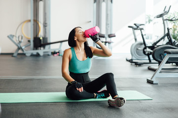 Fototapeta na wymiar Young woman drinking water in gym,