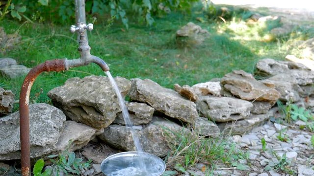Strong water from old faucet in the garden on green background. Footage for films about wasting resources, ecology, energy saving, sustainability, water waste, domestic economy or saving money ideas.