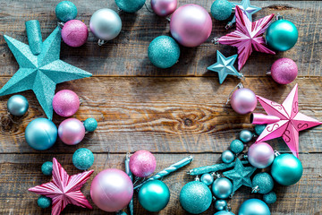 Christmas decoration frame. Pink and blue stars and balls near pine branches on wooden background top view copyspace