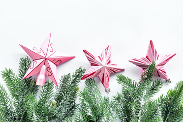Christmas toys. Pink stars near pine branches on white background top view copyspace
