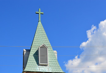 Old Christian cross on a church steeple with a bright blue sky background