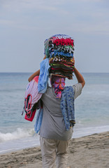 Bali-Lombok: Fliegende Händlerin am Strand mit bunten Tüchern auf dem Kopf