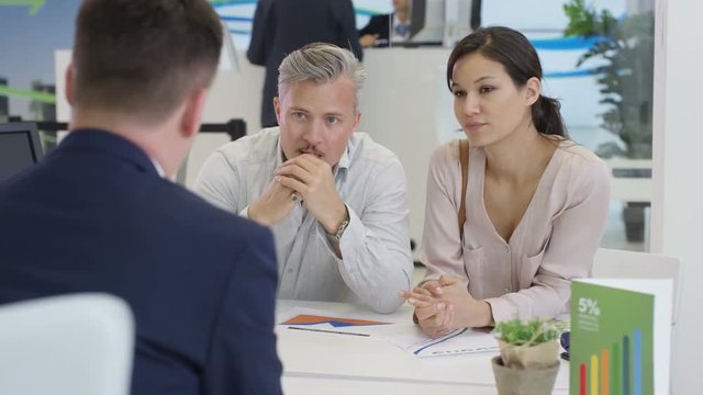  Modern city bank, couple talking to adviser & hoping to get a loan