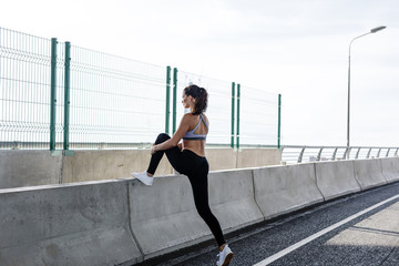 Outdoors workout. Side view of female jogger stretching legs.