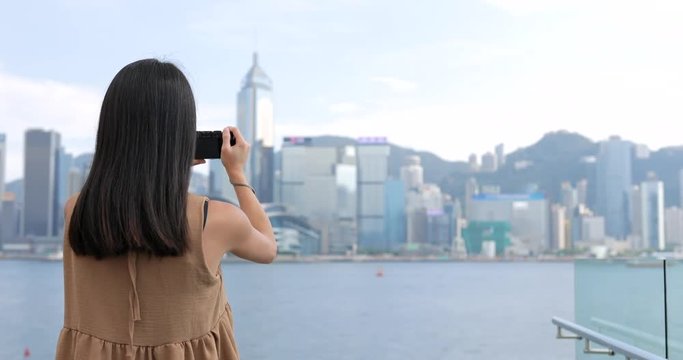 Young Woman taking photo with cellphone in Hong Kong Victoria harbor