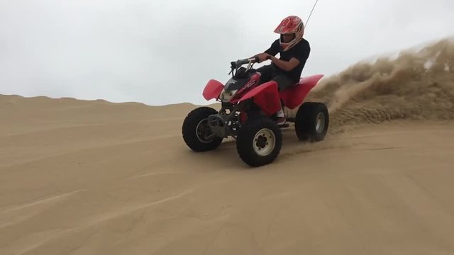 Ragazzo con quad su dune di sabbia, slowmotion