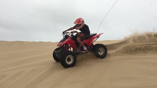 Ragazzo con quad su dune di sabbia, slowmotion