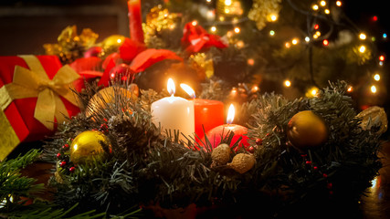 Fototapeta na wymiar Beautiful Christmas background of burning candles, glowing lights and Advent wreath in living room