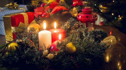 Three burning candles on advent wreath at living room