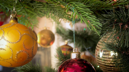 Closeup photo of golden baubles hanging on decorated Christmas tree