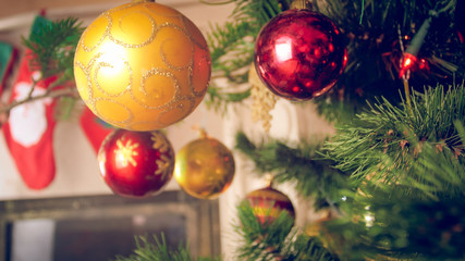 Closeup image of red and golden baubles hanging on Christmas tree