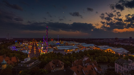 Das Münchner Oktoberfest von oben als Totale am Abend mit bunten Lichtern
