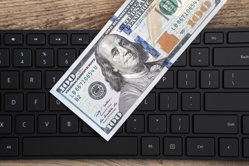 Computer keyboard and hundred dollar bill. Concept of remote work in the Internet
