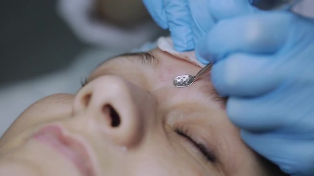 Cosmetician using a needle and doing shots to client's face