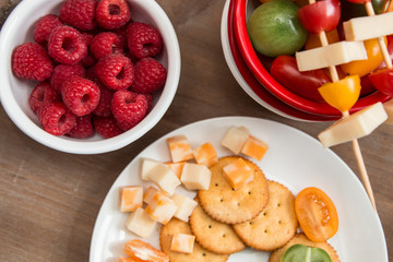 Snack idea, crackers, cheese, tomatoes, mandarin in enameled bowls 