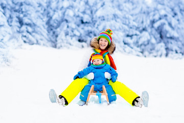 Fototapeta na wymiar Mother and baby on sleigh ride. Winter snow fun.