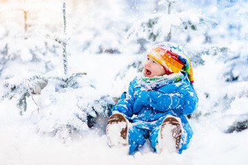 Fototapeta na wymiar Baby playing with snow in winter. Child in snowy park.