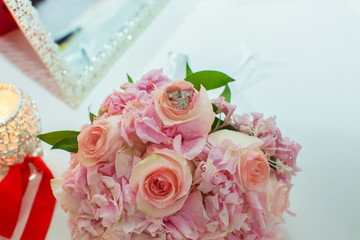 Wedding bouquet of pink roses and wedding rings on a wooden table. Copy space. The concept of a wedding, party, love and family and rings