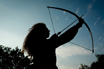 Naklejka premium Red haired girl shoots from the bow
