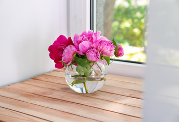 Vase with beautiful peony flowers on windowsill