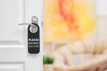Open door with sign PLEASE DO NOT DISTURB on handle at hotel