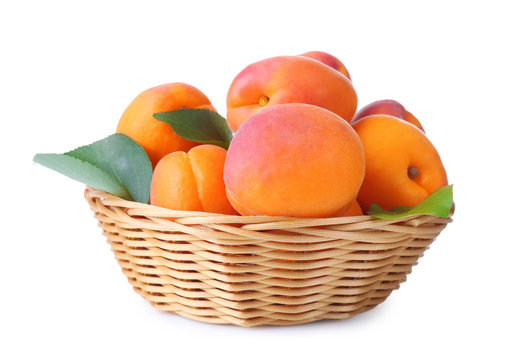 Wicker basket with fresh apricots on white background