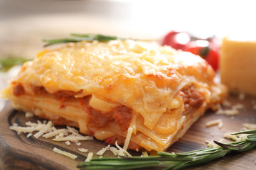 Portion of tasty lasagna on wooden board