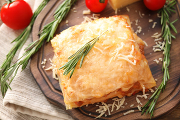 Portion of tasty lasagna on wooden board