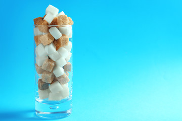 Glass with different types of sugar on color background