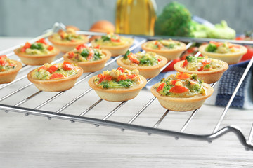 Baking grid with broccoli quiche tartlets on table
