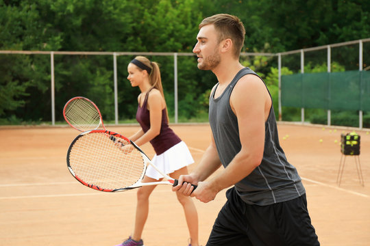 Young man and woman playing tennis on court