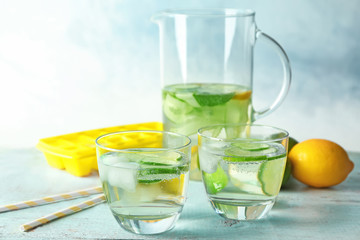 Delicious refreshing water with cucumber in glasses on table