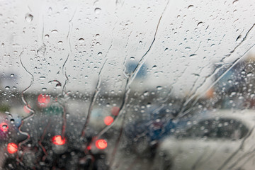 Blur city life through windshield : Drops of rain on car's mirror