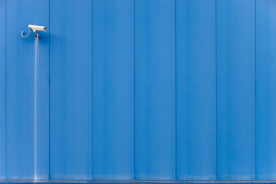 Security camera on metal blue wall
