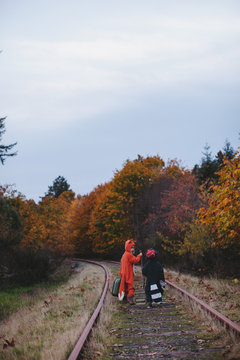 Kids dressed up like fox and raccoon walking on train tracks