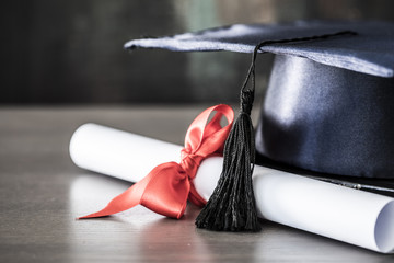 Graduation hat and diploma on table - obrazy, fototapety, plakaty