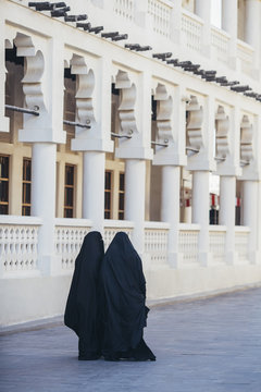 Two women in abayas walking in Doha