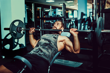Very Strong bearded man doing bench press workout in gym