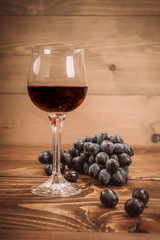 Glass of red wine and grapes on rustic wood table