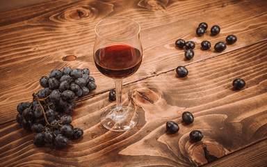 Glass of red wine and grapes on rustic wood table