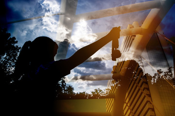Blurred of silhouette Businesswoman hands raised and holding gold medals, show successful against modern building background. Concept of Winners success award and appreciation.